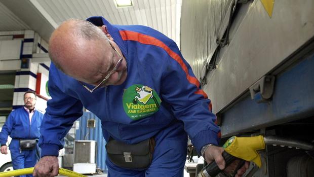 Un empleado llena el depósito de un camión de transporte de mercancias agrícolas
