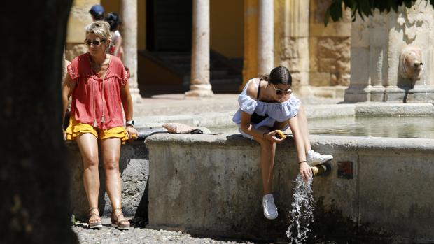 Dos turistas se refrescan en el Patio de las Naranjas
