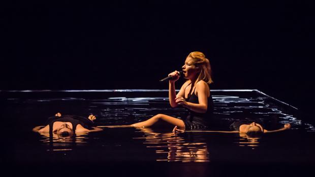 Joana Melo, rodeada de dos bailarines, cantando en el agua del montaje de Quorum Ballet