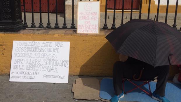 El novillero, cubierto bajo un paraguas, junto al cartel en el que exigía una novillada en San Miguel