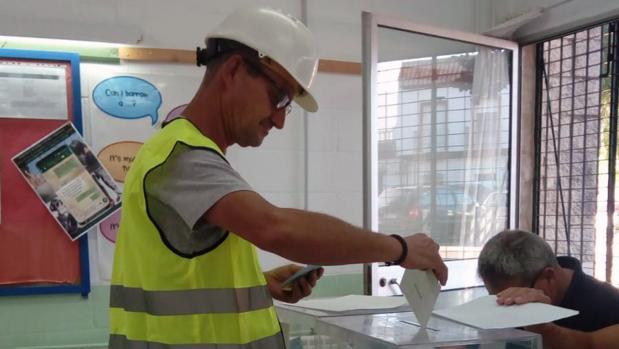 Uno de los padres de alumno votando con casco y chaleco amarillo