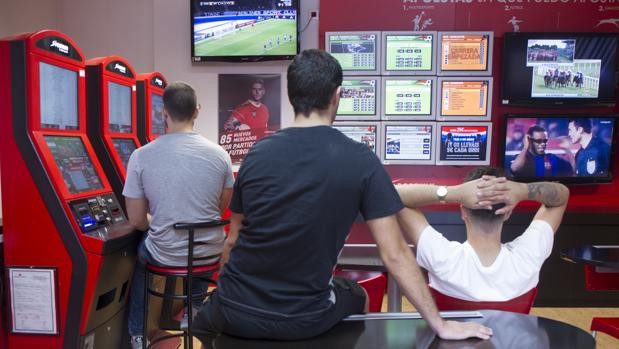 Varios jóvenes, ante las pantallas de apuestas deportivas de un salón de juegos