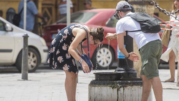 Unos turistas se resfrescan en una fuente en el centro de Sevilla