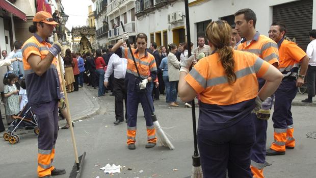 Varios operarios de Lipasam limpiando la calle tras pasar la hermandad del Buen Fin