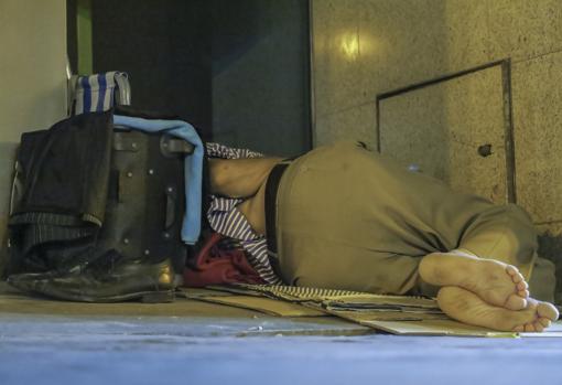 Una persona sin hogar duerme en un portal en Sevilla